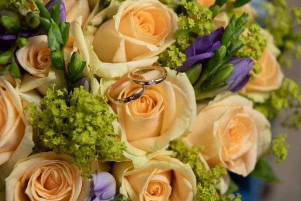 Buquê com belas rosas e anéis de casamento — Fotografia de Stock