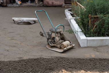 Titreşimli plakalı inşaatçı, beton dökmek için taban kumu mühürler.