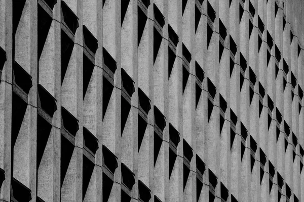 concrete building with a shadow in the form of triangles in the window openings. Abstraction and architecture