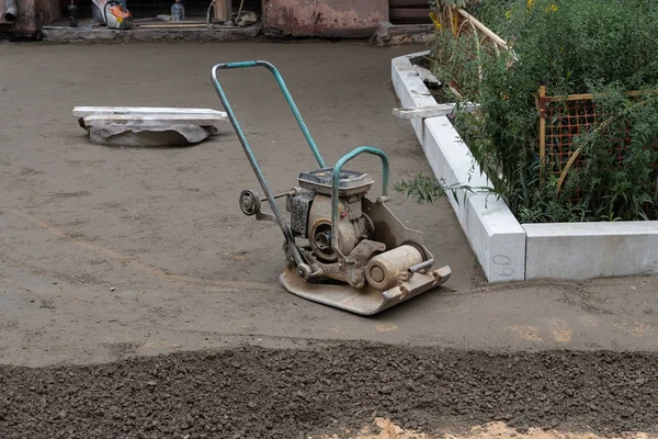Строитель с вибрационными плитами уплотняет основание песком для заливки бетона . — стоковое фото