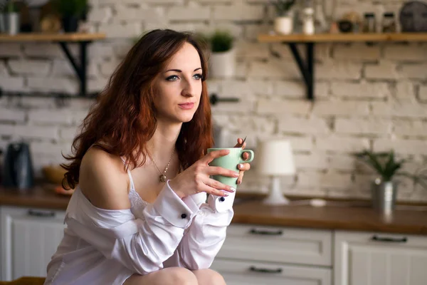 Schattig mooi charmant vrolijk vrij trendy stijlvol meisje drinken koffie, zittend op tafel aanwerk blad in moderne lichte witte keuken — Stockfoto