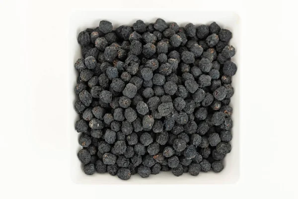 Schwarze Trockenfrüchte. Trockene Beeren. Gesunde Ernährung. Schwarze Preiselbeere in einer weißen Schüssel auf weißem Hintergrund. Ansicht von oben — Stockfoto
