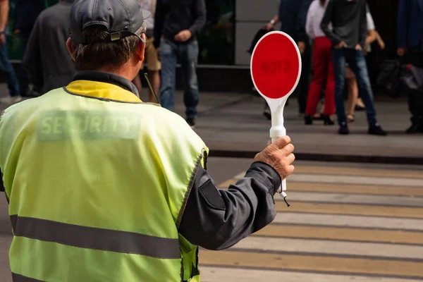 Controlador de tráfico con una señal de stop ayuda a los peatones cruzar la carretera — Foto de Stock