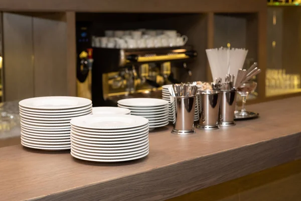 Bar mostrador con platos limpios de cerca. Barroom en el restaurante, listo para trabajar. Fondo del café. Utensilios de cocina, utensilios de cocina (tazas, una pila de platos, platillos, cucharas, una tetera) en el bar en la cafetería — Foto de Stock