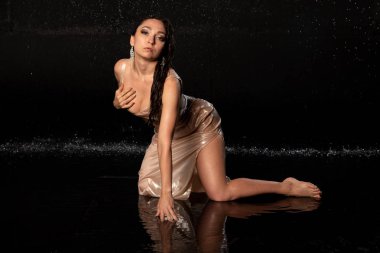 Aqua photostudio 'da güzel seksi manken, siyah arka planda seksi ıslak kız, suda oturan çekici kız, su fotoğrafçılığı.,