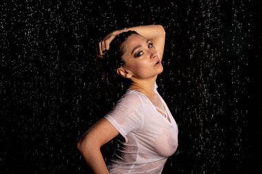 seksi kadın damlacıkları, su studio ile koyu arka plan üzerinde beyaz t-shirt ve şort giyen genç ifade ıslak