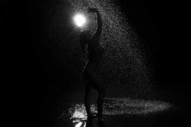 Duştaki seksi kadın. Suyun altındaki çekici, çıplak kadın siyah arka planda damlıyor..