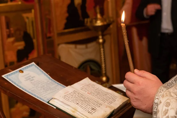 Las manos del sacerdote encienden velas —  Fotos de Stock