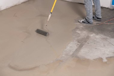 Interior of apartment under construction. Mirror smooth surface of the floor. Floor covering with self leveling cement mortar. Roller application clipart