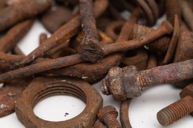 Beyaz zemin üzerinde paslı metal parçalardan oluşan bir dağ. Seçici odak