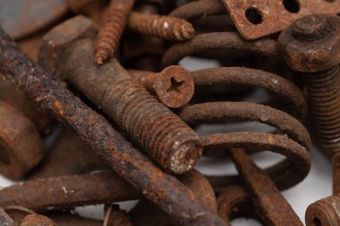 Beyaz zemin üzerinde paslı metal parçalardan oluşan bir dağ. Seçici odak