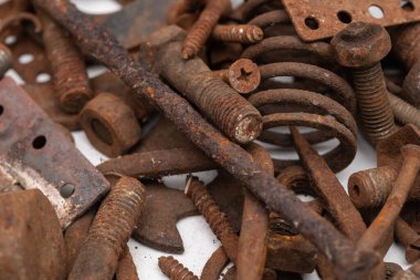 Beyaz zemin üzerinde paslı metal parçalardan oluşan bir dağ. Seçici odak