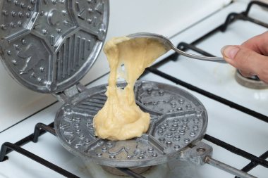 Evde waffle ve kurabiye pişirmek. Hamuru önceden ısıtılmış bir tencereye koymak.