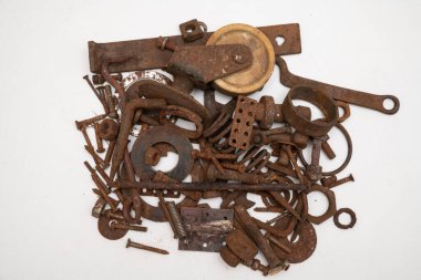 Beyaz zemin üzerinde paslı metal parçalardan oluşan bir dağ.