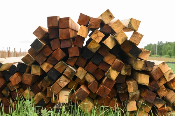 Stack of wooden bars in warehouse. Stacked wooden beams of square section.