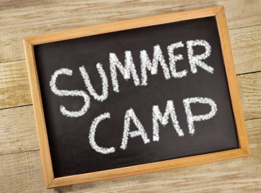 Ahşap bir masa bir tahtaya tebeşir ile yazılı metin yaz kampı