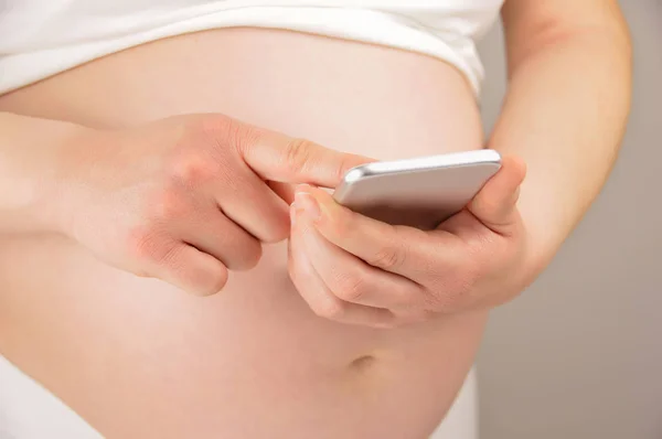 Eine Schwangere Frau Mit Einem Mobiltelefon Vor Weißem Hintergrund — Stockfoto