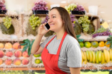 shopwoman meyve bir akıllı telefon kullanarak önlük ile saklamak