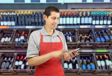 shopman erkek önlük ile bir akıllı telefon bir şaraphane kullanır.