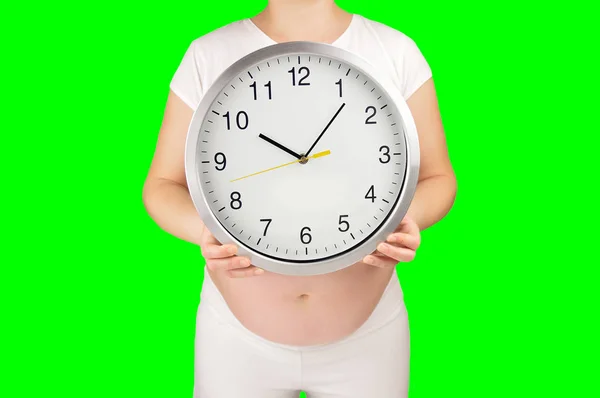 一个怀孕的女人给你看一个时钟 而孤立在白色背景隔离的绿色背景上的开关与色度键 — 图库照片