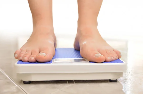 体重計で体重を測定する若い女性の足 — ストック写真