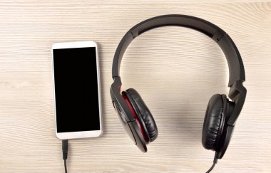 Akıllı telefon ile ahşap masa üzerinde siyah kulaklık