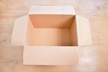 Tahta yüzeyde boş, açık karton bir kutu vardı.