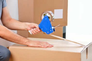 Atış tanımlanamayan bir genç adamın evde bandı ile bir karton kutu kapatma