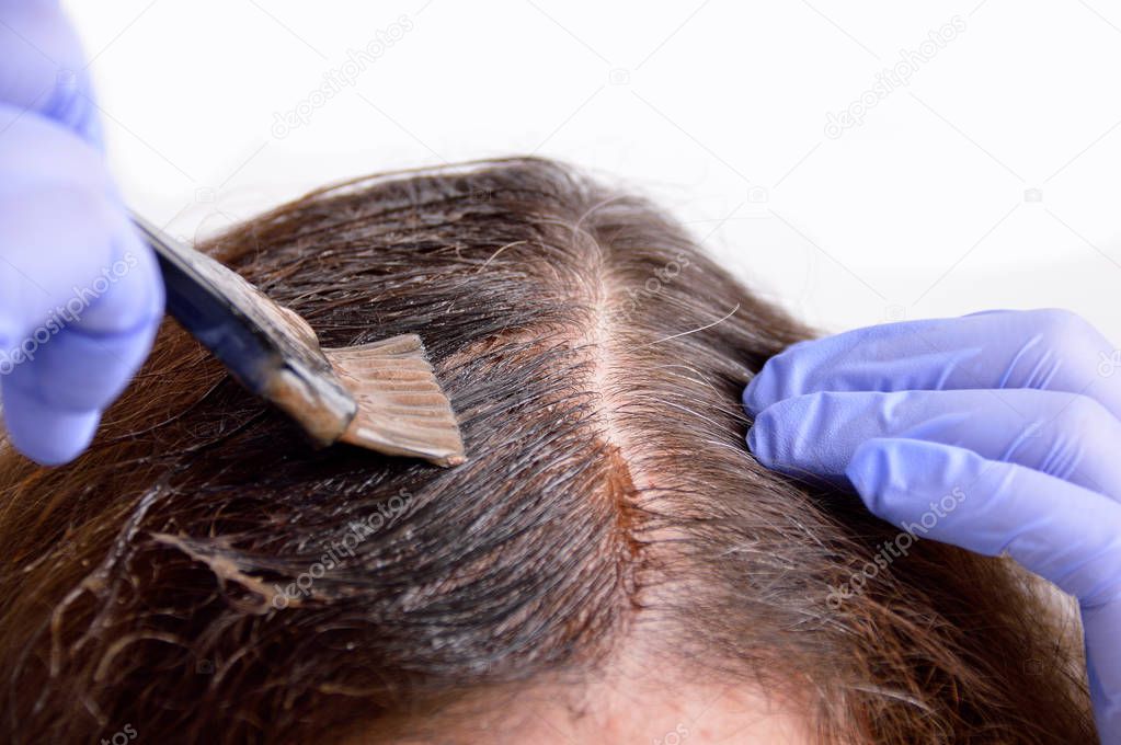 Close-up a brunette woman dying her hair with white background