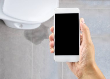 Tuvalette bir su sızıntısı onarım profesyonel aramak için bir akıllı telefon tutan bir el