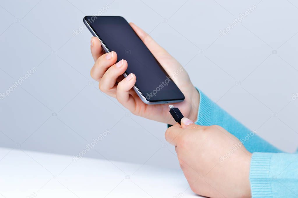 Woman hands plugging a charger in a smart phone