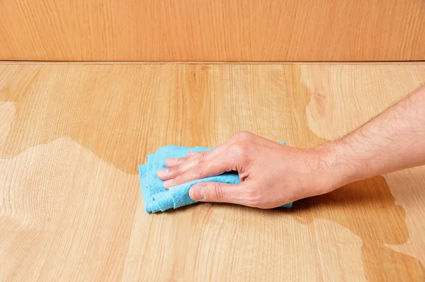 青いスポンジで木製のラミネートパケット床を拭く男の手 — ストック写真