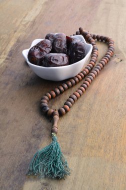 Tarihleri meyve ve tespih natürmort, ahşap arka plan üzerinde