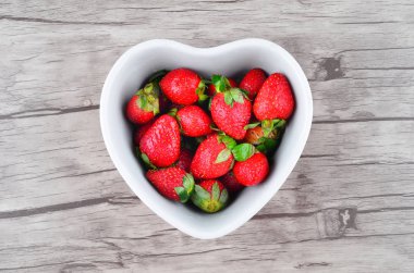 Ahşap arka plan üzerinde kapta iştah açıcı çilek