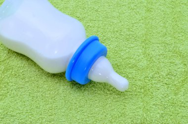 Yeşil havlu üzerine bir bebek için süt şişesiyle
