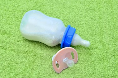 Emzik ve bebek şişe ile yeşil havlu üzerine bir bebek için süt