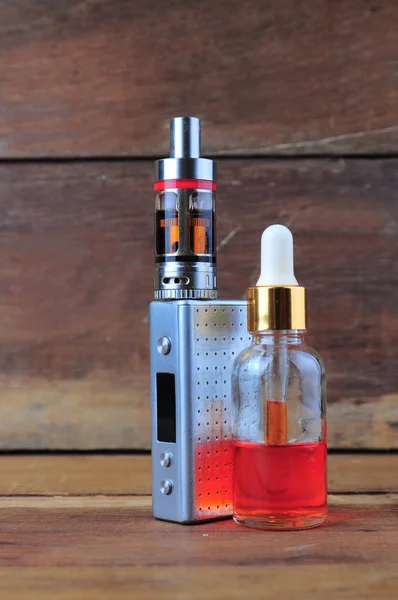 E-cigarette or vaping device with liquid on wooden background