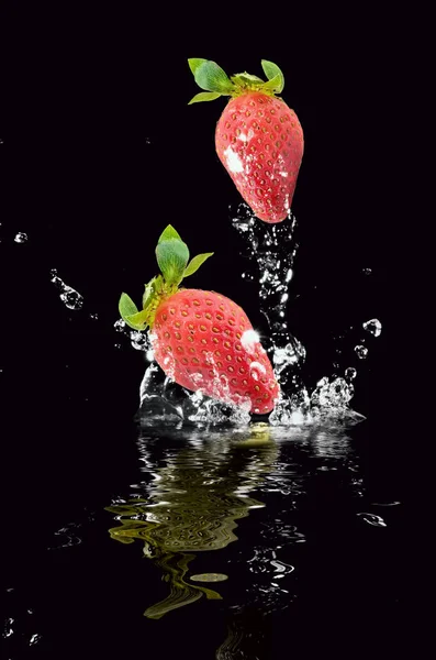 草莓飞溅在黑色背景 — 图库照片