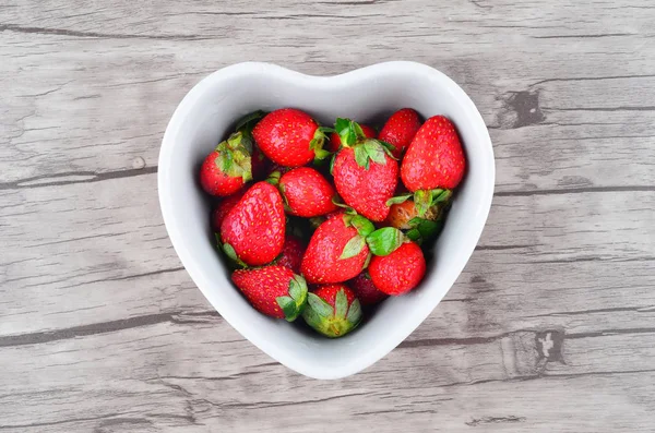 Ahşap arka plan üzerinde kapta iştah açıcı çilek
