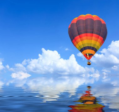 Su yansıması ile mavi gökyüzü üzerinde uçuşta renkli sıcak hava balonları