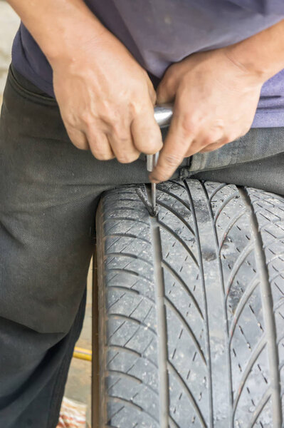 На рисунке показано, что ручная механика чинит протекающие шины и уплотняющие шины.
