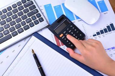 Hesap makinesi ile grafik, grafik, klavye, fare üzerinde ahşap masa üzerinde el