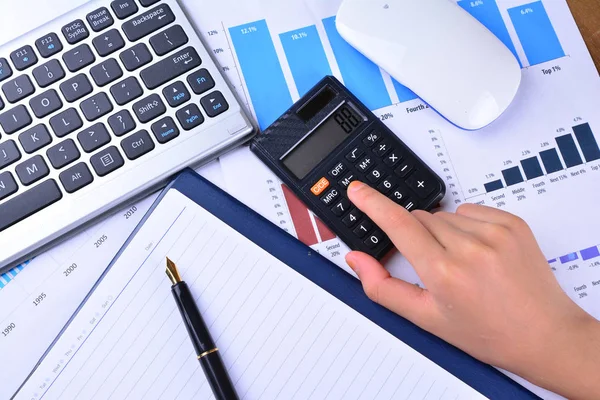 Hesap makinesi ile grafik, grafik, klavye, fare üzerinde ahşap masa üzerinde el
