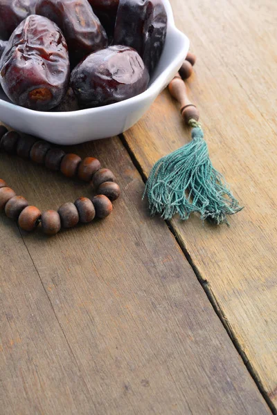 Tarihleri meyve ve tespih natürmort, ahşap arka plan üzerinde