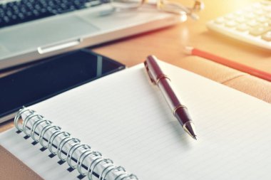 Defter ile hesap makinesi, klavye ve kalem masada