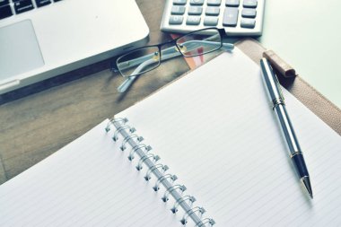 Defter ile hesap makinesi, klavye ve kalem masada