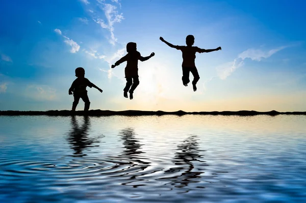 Silueta Niños Saltando Sobre Sol Levantándose —  Fotos de Stock