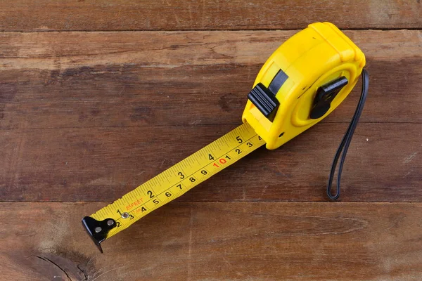 yellow tape measure on wood background