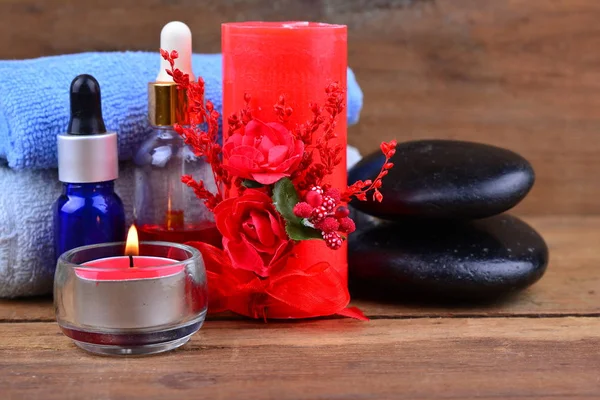 Red romantic candle and spa oil with towel and zen stone