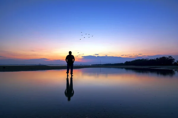 日没時に飛んでいる鳥たちを探している男性のシルエット — ストック写真